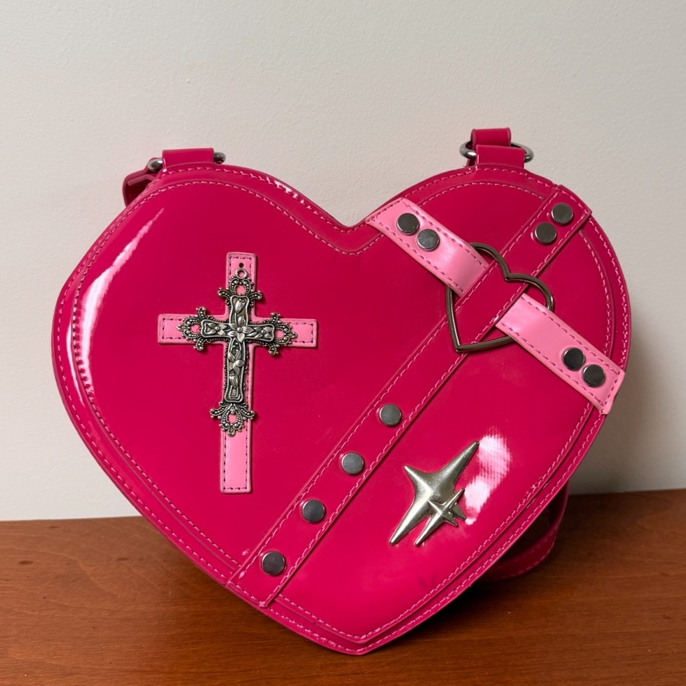 Hot pink heart-shaped crossbody bag with gothic / punk inspired hardware.